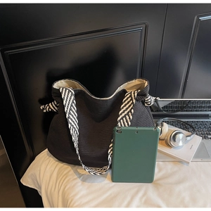 Détail d'un grand sac cabas en velours côtelé noir avec des bretelles tressées bicolores
