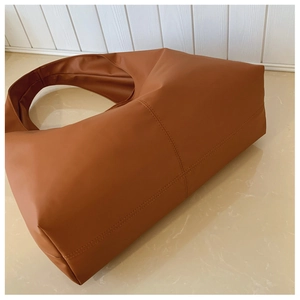Detail view of caramel brown tote bag showing professional cross-stitch and matte leather texture