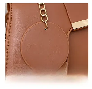 Close-up of brown leather saddle bag with fashion charm and gold chain detail