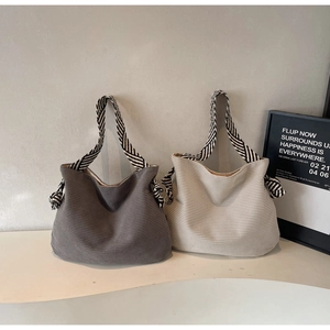 Détail de sacs fourre-tout en maille rayée gris et crème avec des poignées tissées chic