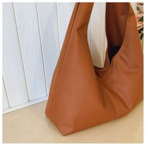Detail of caramel brown hobo tote bag in soft matte leather with seamless handle design