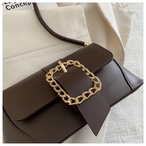 Close-up of deep brown leather baguette bag with a signature large gold chain buckle