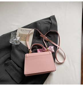 Rosafarbene PU-Handtasche auf grauem Blazer mit gemustertem Halstuch und Golddetails