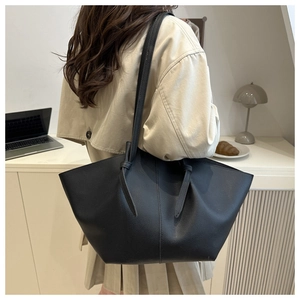 Litchi texture black tote bag with knot strap detail shown on shoulder in a workspace