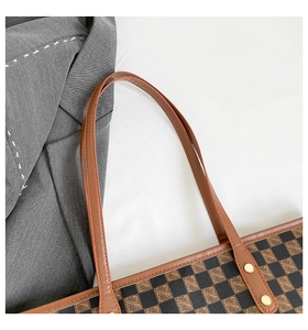 Dettaglio dei manici in pelle marrone con rivetti dorati sulla borsa tote monogram