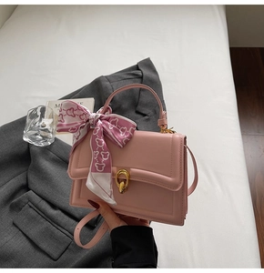 Dettaglio borsa a mano in pelle rosa con fibbia ad anello dorata e manico in foulard