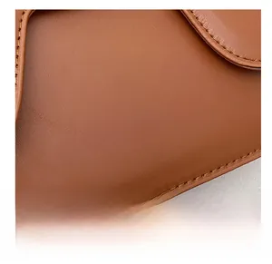 Detail of brown leather saddle bag with fashion lettering and precise stitching