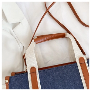 Detail of dark blue denim tote bag with brown leather trim and canvas strap for daily commute