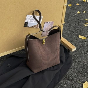 Sac seau en daim marron avec fermoir doré dans un décor extérieur automnal chic