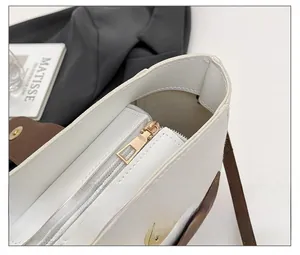 Dettaglio macro della cerniera in metallo dorato su borsa a secchiello bicolore alla moda