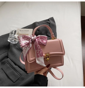 Detail der rosa Kunstledertasche mit goldenem Verschluss und dekorativem Seidenschal