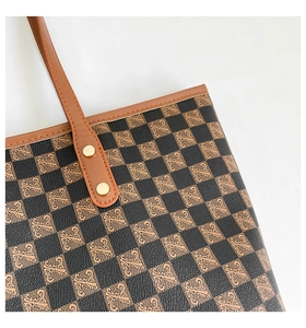 Dettaglio della borsa tote a quadri vintage con manici in pelle e rivetti dorati