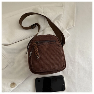 Detail of vintage corduroy crossbody bag with woven zipper pull and adjustable strap