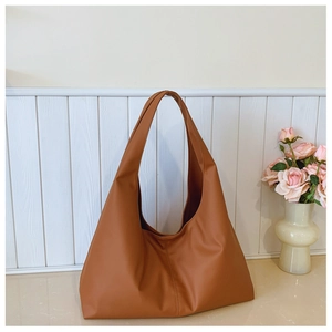 Close-up of a large camel leather hobo bag with distinctive vertical stitching detail