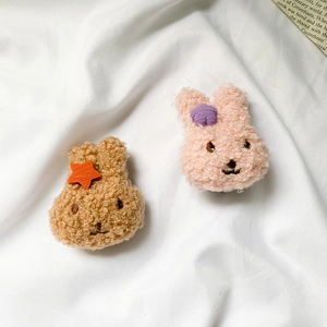 Detailed view of plush rabbit phone grips in brown and pink with embroidery