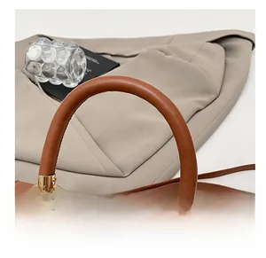 Detail of brown saddle bag featuring smooth curved handle and gold metal hardware link