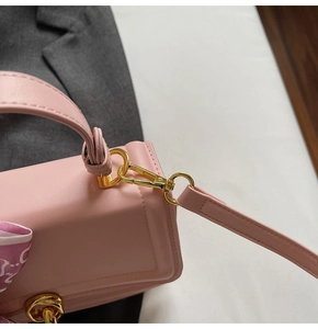 Detailaufnahme einer rosa Ledertasche mit goldenen Metallhaken und Seidenschal-Dekor