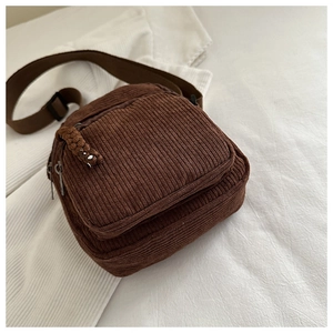 Detail of dark brown corduroy crossbody bag with zipper pocket and adjustable strap