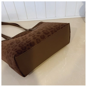 Detailed view of leopard print tote bag with dark brown leather base and neat stitching