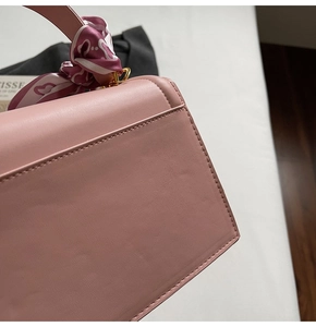 Makro-Detail der rosa Ledertasche mit Rückentasche und dekorativem Seidenschal-Griff