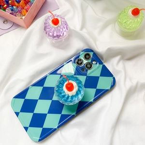 Detail of 3D jelly cupcake phone grip with red cherry on blue and green plaid phone case