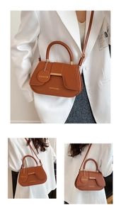 Detailed close-up of brown half-moon crossbody bag with golden buckle and fashion charm