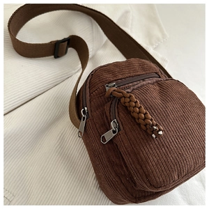 Close-up of brown corduroy crossbody bag with woven rope pullers and adjustable strap
