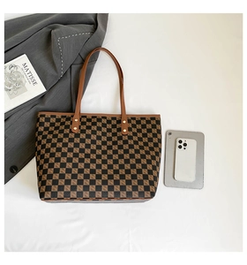 Vista dettagliata della borsa tote a scacchi marrone con manici in pelle e accessori vari