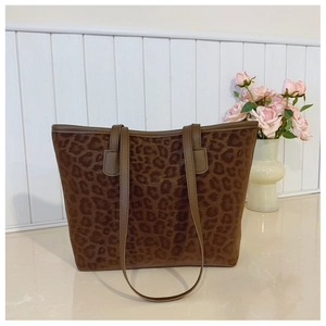 Detail of leopard print tote bag with brown leather handles on marble surface
