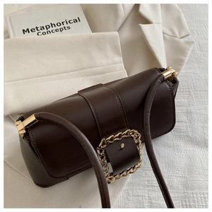 Close-up of a dark brown matte leather baguette bag with a bold gold square chain buckle