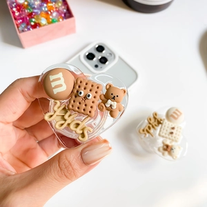Détail d'un support de téléphone en cœur avec breloques 3D ours, biscuit et bonbon