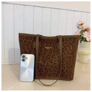 Detail of leopard print tote bag next to a smartphone for clear size comparison