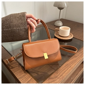 Detail of caramel leather handbag with gold metal clasp on a cozy cafe table setting