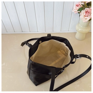 Detail of vintage black tote bag interior showing beige lining and silver magnetic buckle