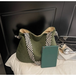 Close-up of deep green corduroy tote bag with textured stripes and woven handles