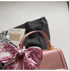 Detail der rosa Lederhandtasche mit herzgemustertem Seidenschal und Gold-Hardware