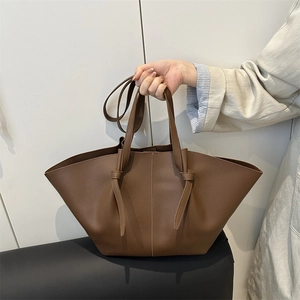 Brown lychee leather tote bag with wing trapezoid design and adjustable knot straps