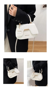 Detail view of white minimalist shoulder bag with gold hardware and fashion pendant charm