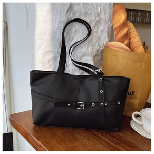 Detail of black faux leather shoulder bag with silver buckles and decorative belts