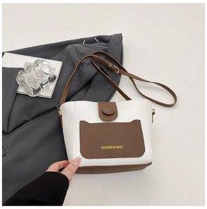 Dettaglio di una borsa a secchiello bianca e marrone con tasca anteriore e tracolla