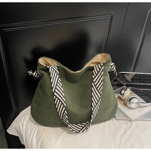 Gros plan d'un sac cabas en velours côtelé vert foncé avec une bandoulière tissée chic