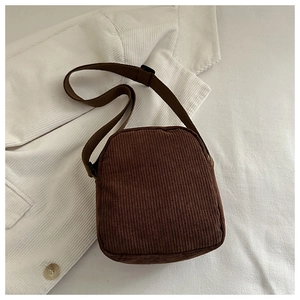 Detail of dark brown corduroy vertical crossbody bag with zipper and adjustable strap