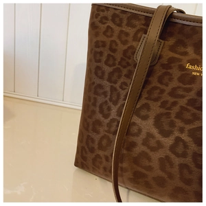 Detail view of leopard print tote bag with gold fashion NEW YORK lettering and strap