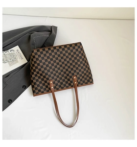 Vista dettagliata di una grande borsa tote a scacchi con cinturini in pelle marrone e rivetti