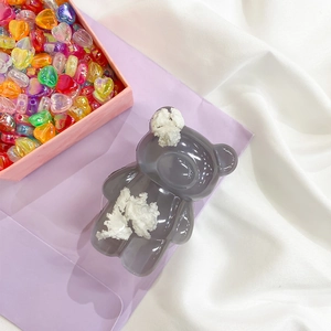 Detailed close-up of dark grey bear hair clip with white pom-poms on a purple background