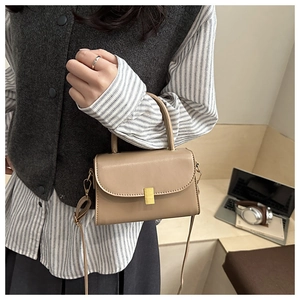 Detail shot of a beige PU leather crossbody bag with a gold buckle for a stylish winter look