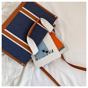Flat lay of spacious denim tote bag showing interior capacity with gadgets and books