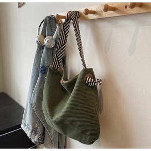Détail du sac fourre-tout en velours côtelé vert foncé avec bandoulière rayée sur cintre