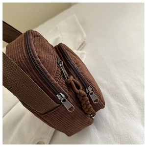 Detail view of dark brown corduroy shoulder bag showing multi-pocket texture and metal zippers