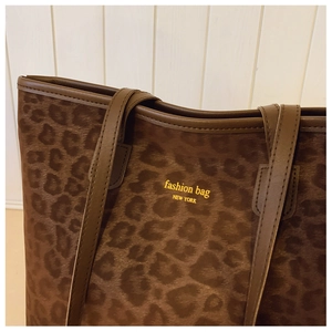 Close-up of leopard print tote bag with faux suede texture and leather trim detailing
